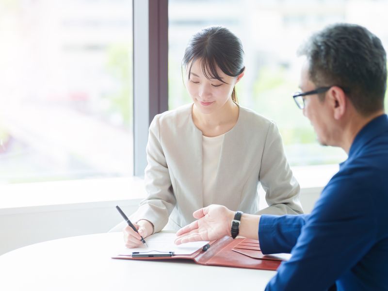 行員と起業家が資料を見ながら話し合っている様子